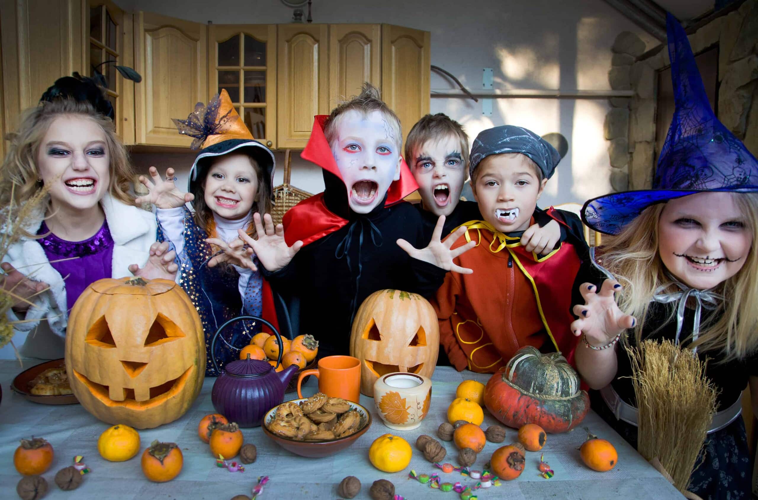 funny halloween jokes - kids in halloween costumes around jack o lanterns