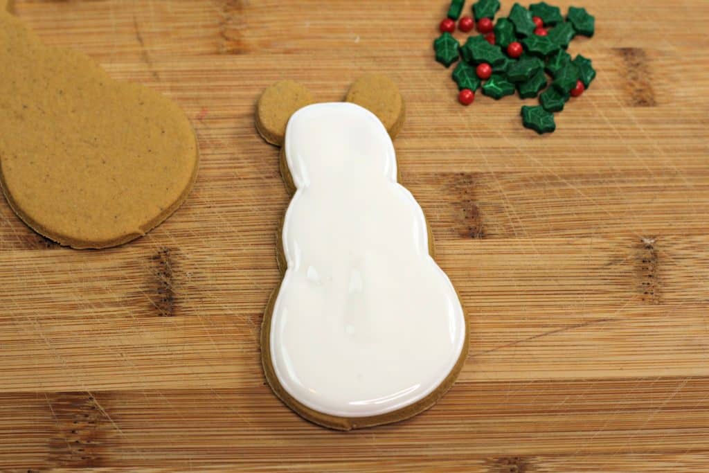 Gingerbread snowman cookie on counter covered in white icing.
