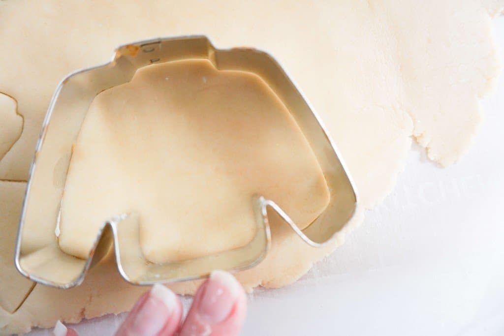 Flattened dough being cut with sweater-shaped cookie cutter
