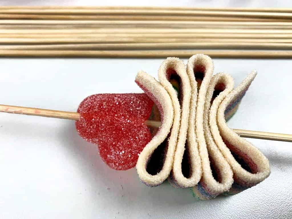Two gummy candies, placed onto a bamboo skewer in process of making candy kabobs.