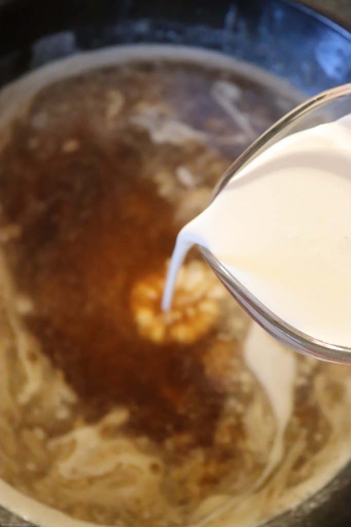 Milk being poured into a bowl out of a glass measuring cup.