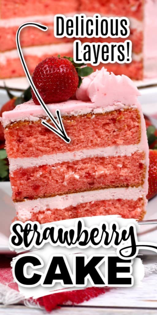 Slice of 3-layer strawberry cake sitting on white plate on wooden countertop with fork on the plate.