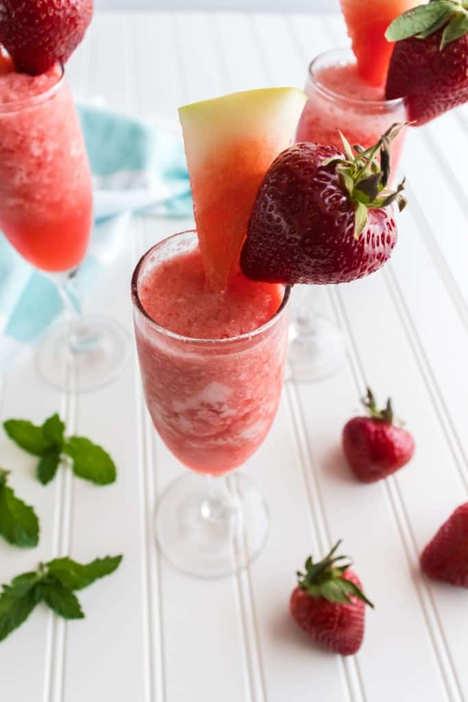 Watermelon Slush in a fluted glass with strawberry and watermelon wedge as a garnish.